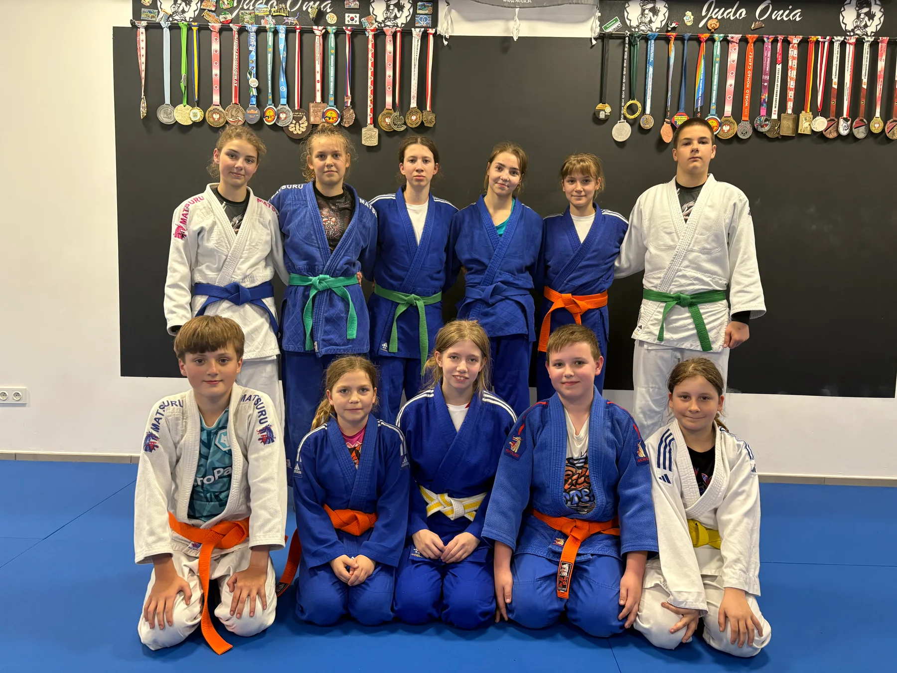 Młodzi judocy Judo Onia w białych i niebieskich judogach z kolorowymi pasami