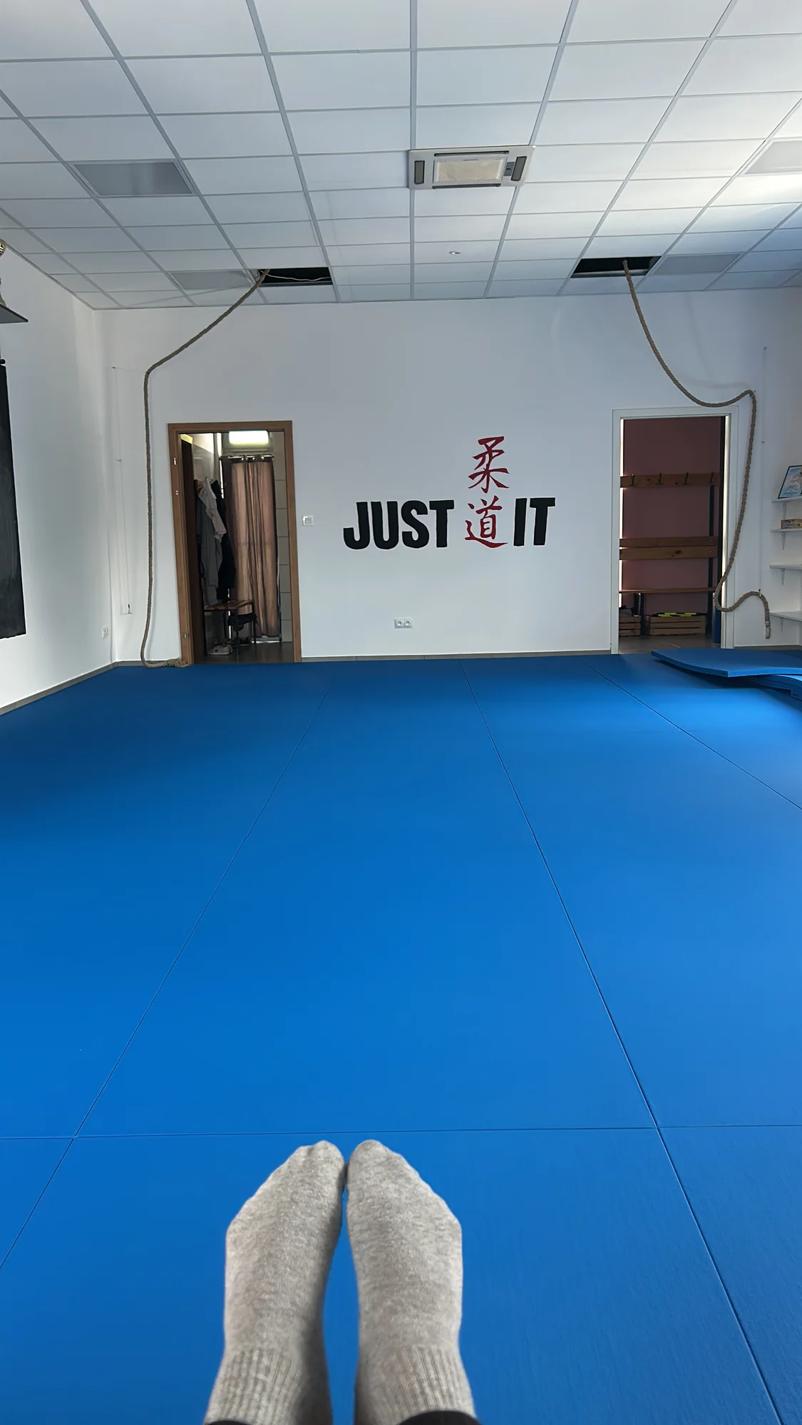 Sala treningowa Judo Onia z niebieską matą i napisem Just Judo It na ścianie